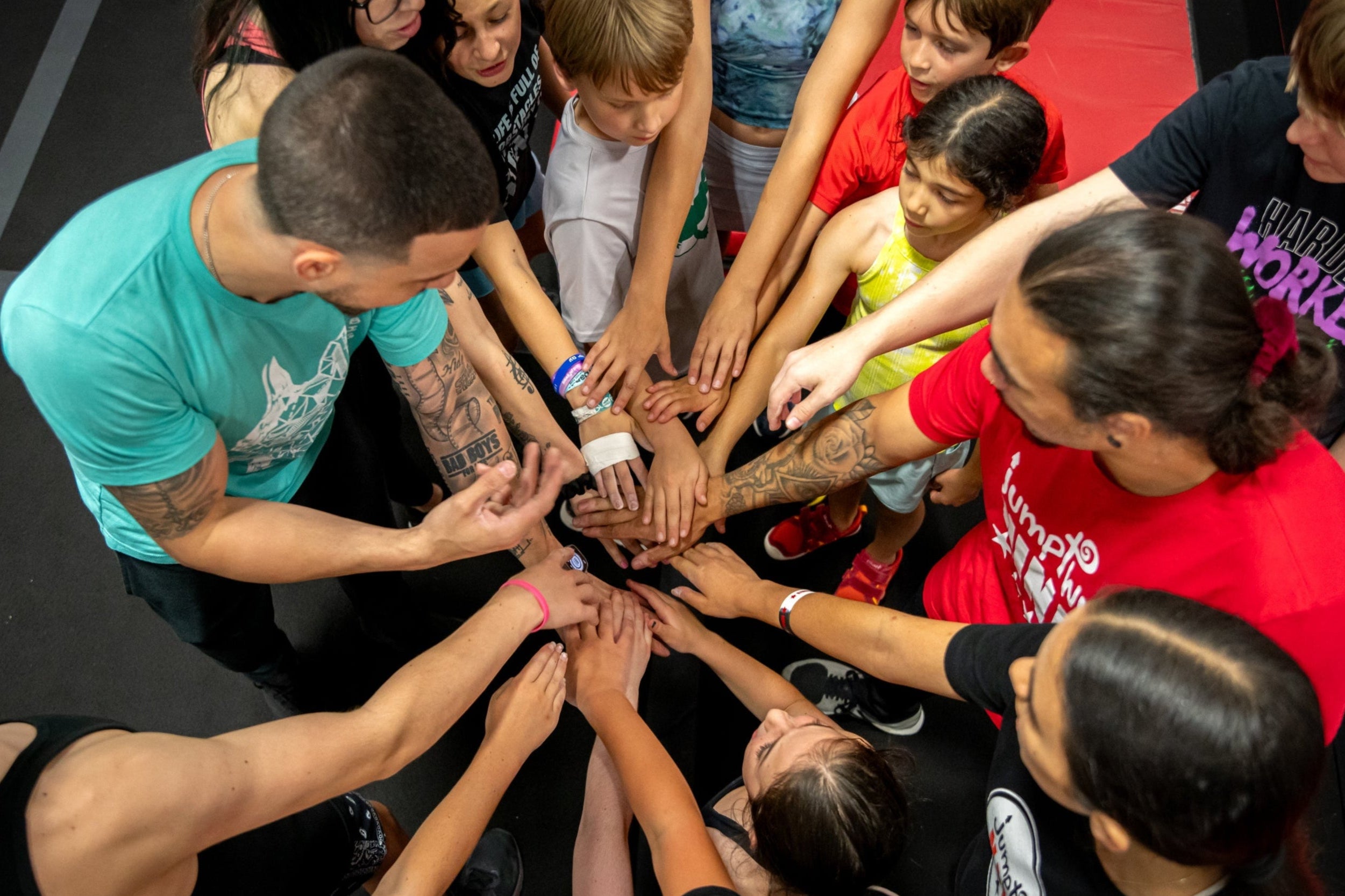 Jumptwist Ninja franchise coaches and students join hands in a team huddle, showcasing the empowering, community-driven spirit of our youth ninja training program—available to franchise in select territories.